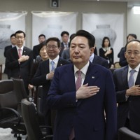 国旗に敬礼する韓国の尹錫悦大統領（手前）＝ソウルで2023年3月7日、聯合AP