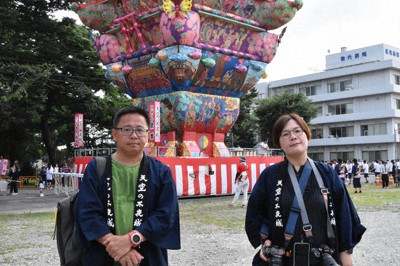 「能代七夕　天空の不夜城」を取材する余若綺さん（右）と江宜信さん。後方は高さ日本一の城郭灯籠「愛季」＝秋田県能代市で2023年8月2日、田村彦志撮影