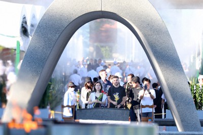 平和記念公園を訪れ、供える花を手に原爆慰霊碑を見つめる人たち＝広島市中区で2023年8月6日午前6時44分、梅田麻衣子撮影