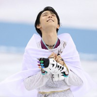 平昌五輪のフィギュアスケート男子で優勝し、連覇を果たした羽生結弦さん。表彰式後に日の丸をまとい、優しくほほ笑んだ＝江陵アイスアリーナで2018年2月17日、佐々木順一撮影