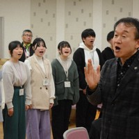 神戸の学生たちとの交流のため訪れた「福島しあわせ運べるように合唱団」の指揮をしながら「しあわせ運べるように」を歌う神戸親和大の臼井真准教授（右）＝神戸市北区で2023年12月27日午前11時51分、山本康介撮影