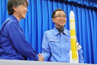 H3ロケット2号機の打ち上げが成功し、記者会見で模型を前に笑顔で握手するJAXAの岡田匡史プロジェクトマネジャー（右）と三菱重工の新津真行プロジェクトマネジャー＝鹿児島県南種子町の種子島宇宙センターで2024年2月17日午後2時2分、吉田航太撮影