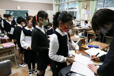 先生に提出物を見せる子供たち＝大阪市内の小学校で2021年1月、小出洋平撮影