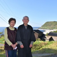 集落で寺を守る岡本満葉さん（右）と妻の八重子さん。右奥には隆起した海岸が見える＝石川県輪島市門前町吉浦で2024年5月2日午後4時9分、国本ようこ撮影