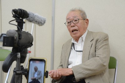 カメラの前で体験を語る小峰秀孝さん＝長崎市岡町で