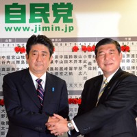 自民党開票センターに入り、石破茂幹事長（右）と握手する安倍晋三総裁＝東京都千代田区の党本部で2012年12月16日午後9時51分、藤井太郎撮影