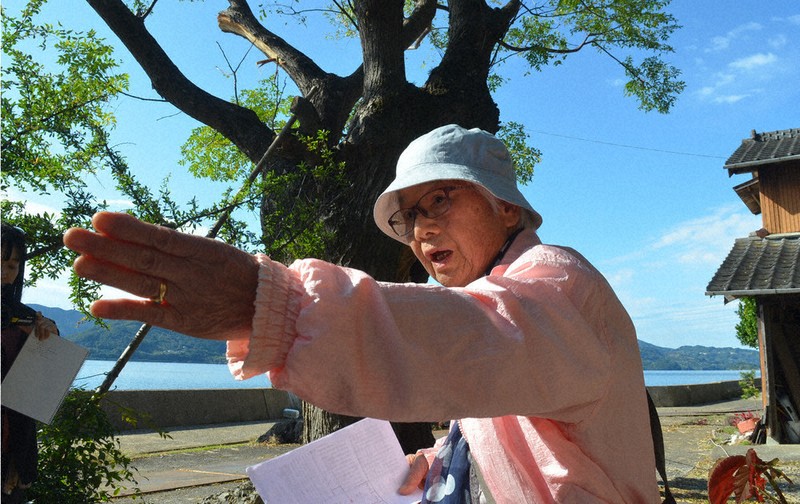 大村湾に面した実家の前で原爆投下後の状況を語る松崎寿々子さん＝長崎県大村市西部町で