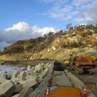 隆起海岸を活用した岬巡りの仮設道路の造成が急ピッチで進む逢坂トンネル工区。冬の荒波を避ける土のうが積まれている＝石川県珠洲市真浦町で2024年12月4日午後3時ごろ、竹中拓実撮影