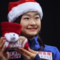 ジュニア女子フリーから一夜明け、クリスマスグッズを手に写真撮影に応じる島田麻央＝フランス・グルノーブルで2024年12月7日、猪飼健史撮影