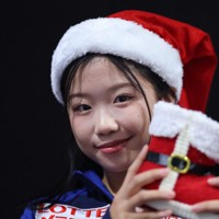 ジュニア女子フリーから一夜明け、クリスマスグッズを手に写真撮影に応じる中井亜美＝フランス・グルノーブルで2024年12月7日、猪飼健史撮影