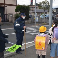 警察官や教諭に見守られ下校する児童＝北九州市小倉南区で16日、山下智恵撮影