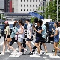 7月、気温が上昇した東京・銀座を行き交う人たち＝共同