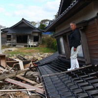 生まれた時から過ごした自宅の屋根で、土砂で流された家具などを見つめる南仁さん＝石川県珠洲市仁江町で2024年11月25日、稲生陽撮影