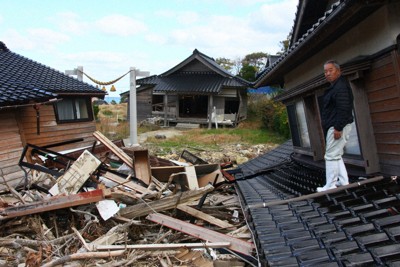 生まれた時から過ごした自宅の屋根で、土砂で流された家具などを見つめる南仁さん＝石川県珠洲市仁江町で2024年11月25日、稲生陽撮影