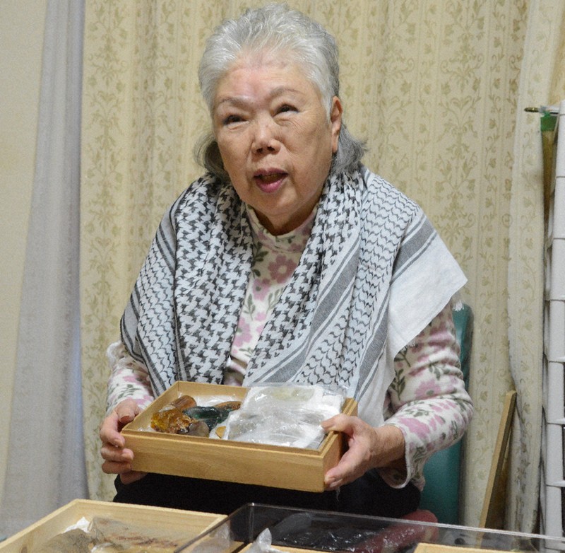 爆心地公園で掘り出した溶けたガラスなどを手に思いを語る竹下芙美さん＝長崎市で