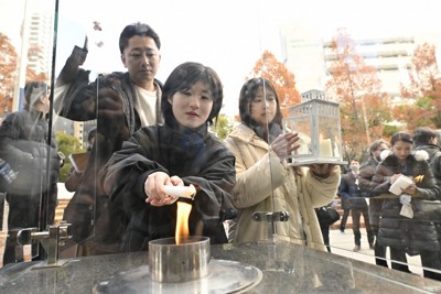 「1・17希望の灯り」を能登半島地震の追悼式典に向けて分灯する人たち＝神戸市中央区の東遊園地で2024年12月14日、小関勉撮影