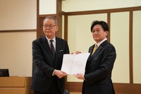 On behalf of education minister Toshiko Abe, who is on an overseas trip, state minister of education Arata Takebe, right, hands a proposal on revisions to curriculum guidelines and other issues to Katsumi Arase, chairman of the Central Council for Education, in Tokyo on Dec. 25, 2024. (Mainichi/Buntaro Saito)