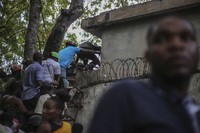 Journalists climb up a wall to take cover from gunfire, after being shot at by armed gangs at the General Hospital in Port-au-Prince, Haiti, on Dec. 24, 2024. (AP Photo/Jean Feguens Regala)