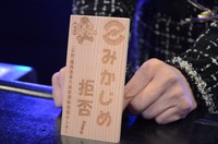 A woman shows a wooden tablet that displays the message, "We refuse gang protection!" along with the Fukuoka Prefectural Police mascot, "Fukkei-kun," in Fukuoka Prefecture on Dec. 5, 2024. (Mainichi)