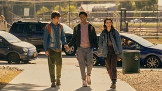 Arthur "Spoon" Spindell, Mickey Bolitar and Ema Winslow smile as they hold hands walking down the street.