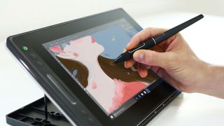 Hand holding stylus over Huion Kamvas Pro 13 tablet