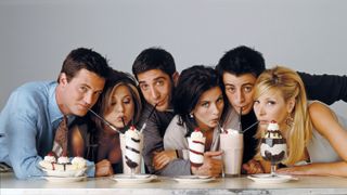 The cast of Friends drinking milkshakes in front of a white background.