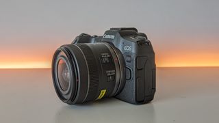 Canon EOS R8 set against a white backdrop with orange glow