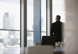 Business person looking our of the boardroom windows onto the cityscape