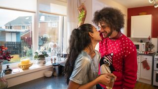 a couple in Christmas attire kisses