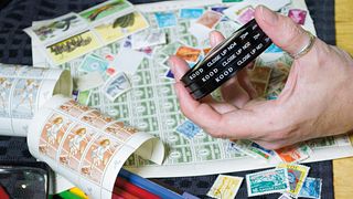 A stack of close-up filters being held above sheets of postage stamps