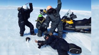 The researchers pose with the 16.7-pound meteorite on a snowscape in Antarctica.