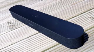 The Sonos Beam soundbar pictured at an angle on a wooden surface.