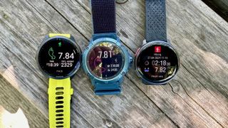 The Garmin Forerunner 965 (left), COROS VERTIX 2S (center), and Polar Vantage V3 (right) sitting on a table together, all showing post-hike result screens.