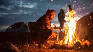 A man stares into a fire.