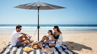 Family relaxing on the beach next underneath the Anker SOLIX Solar Umbrella