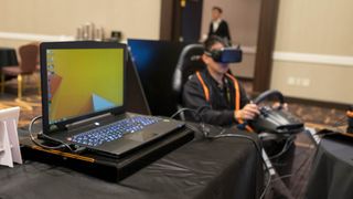 A gamer using a VR headset hooked up to a laptop