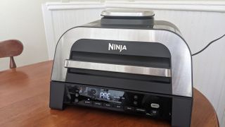 En airfryer av typen Ninja Foodi Smart XL 6-i-1 Indoor Grill & Air Fryer på en kjøkkenbenk.