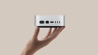 A hand holding up the new Mac mini M4