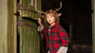 Christian Convery as Gus coming out of a shed in the woods during the Netflix show, Sweet Tooth.