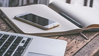 An iPhone beside a laptop.