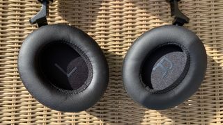 Shure Aonic 50 Gen 2 headphones detail with cups rotated to lie flat, on a wicker chair