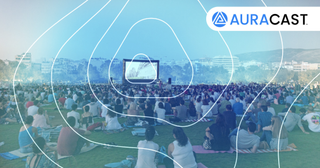 Bluetooth Auracast being used at a festival, on a big screen with people watching and listening