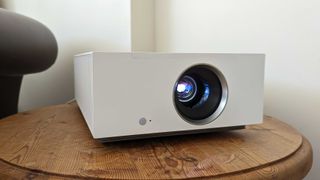 Bästa projektor: En vit LG CineBeam HU710PW står på ett litet soffbord i ett hörn.