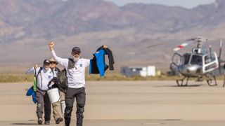 a man walks through the desert pumping his hand in the air