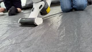 vacuuming the tent floor with a white handheld vacuum