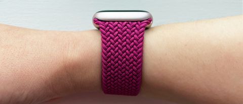 A side view of the magenta-colored Apple Braided Solo Loop attached to a light pink Apple Watch on a woman&#039;s wrist.