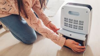 Is dehumidifier water safe to drink? image shows woman emptying a dehumidifier