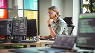 Male software developer using Java 17 while sitting at computer desk.