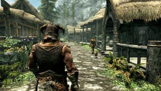 Skyrim screenshot of a player character walking down a flagstone path in a village, thatched cottages either side.