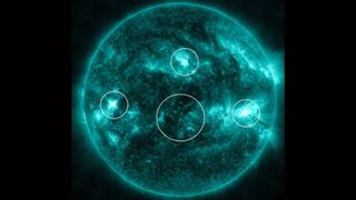 A picture of the sun with a green filter showing four simultaneous solar flares circled